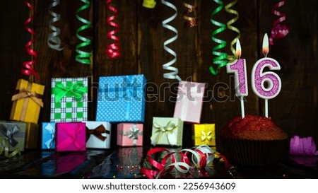 Party birthday background with number  16. Beautiful background anniversary copy space with burning candles. Gift boxes with decorations.