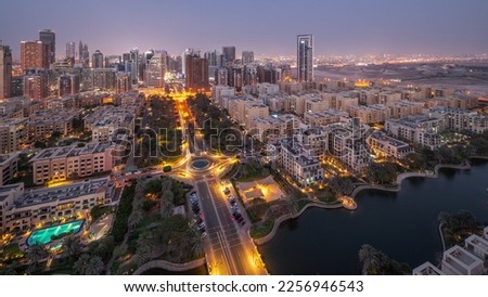 Skyscrapers in Barsha Heights district and low rise buildings in Greens district aerial day to night transition timelapse. Dubai skyline with palms and walking area nead pond
