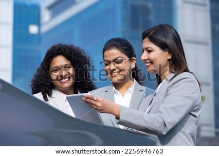 Businesswoman team working online outdoors using a tablet computer and smiling