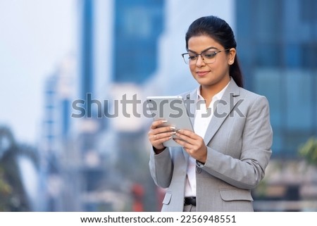 Happy businesswoman holding digital tablet outside office building.