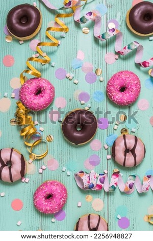 Donuts, Berliner, Krapfen with streamers and confetti. Colorful picture of carnival, birthday and fasching, green background, top view