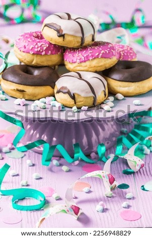 Donuts, Berliner, Krapfen with streamers and confetti. Colorful picture of carnival, birthday and fasching, pink background, vertical