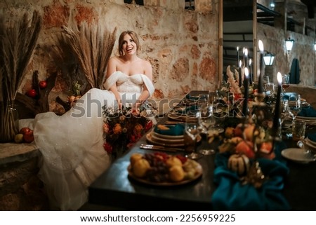 Beautiful bride by wedding table, richly decorated with flowers and candles