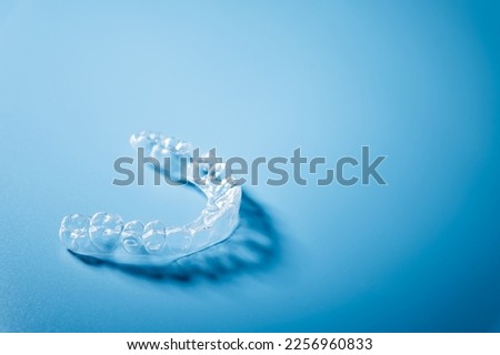 Close up invisible aligners on the blue background with copy space. Plastic braces dentistry retainers to straighten teeth Royalty-Free Stock Photo #2256960833