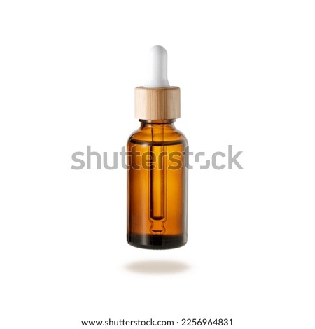 Glass dropper bottle with cover of bamboo wood for face serum or essential oil or pharmaceutical tincture. Bamboo and glass bottle flying isolated on white background. Zero waste concept. Royalty-Free Stock Photo #2256964831