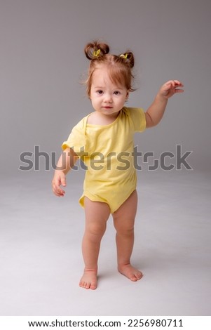 baby girl starting to walk takes her first steps on a white background Royalty-Free Stock Photo #2256980711