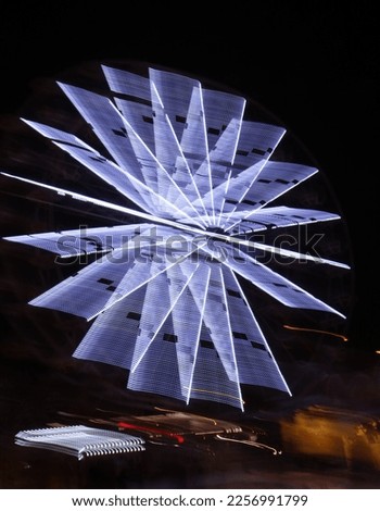 Motion effect, light trails. Rotating illuminated attraction in amusement park at night. Light painting. Lines waves against a black background.