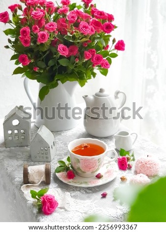 Selective focus of delicious tea with pink baby rose flowers on white background. 