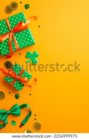 St Patrick's Day concept. Top view vertical photo of green present boxes with orange ribbon bows trefoils clover shaped confetti bow tie and gold coins on isolated yellow background with empty space