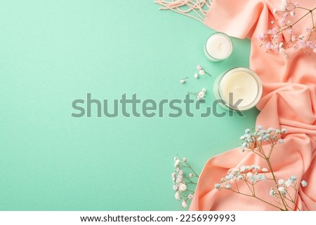 Hello spring concept. Top view photo of candles in glass holders blue and pink gypsophila flowers and soft scarf on isolated turquoise background with blank space