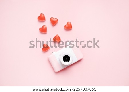 cute abstract little pink camera with candy hearts on a pastel pink background. copy space. top view. flat lay