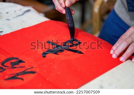 An old Chinese calligrapher is writing Chinese Spring Festival couplets Royalty-Free Stock Photo #2257007509