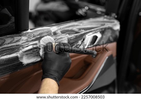 Washing with foam and detergent using a brush on the inner surface of the car door. Car detailing service. Royalty-Free Stock Photo #2257008503