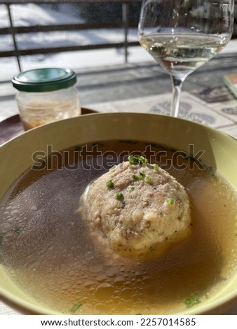 traditional austrian dish of beef broth with a knoedel or dumpling served on a wooden table in the sun