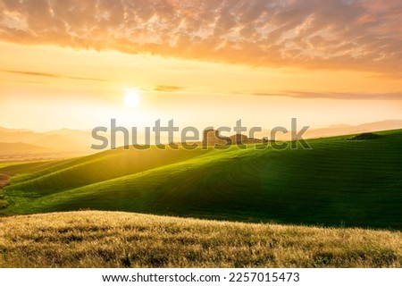 amazing sunset among green spring hills in highland farm with castle , mountains and picturesque colorful sunset on background of landscape Royalty-Free Stock Photo #2257015473