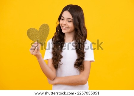 Lovely romantic teenage girl hold red heart symbol of love for valentines day isolated on yellow background. Happy teenager, positive and smiling emotions of teen girl.