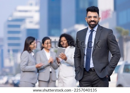 Outdoor Portrait of young Asian Indian businessman wearing business suit and looking at camera.