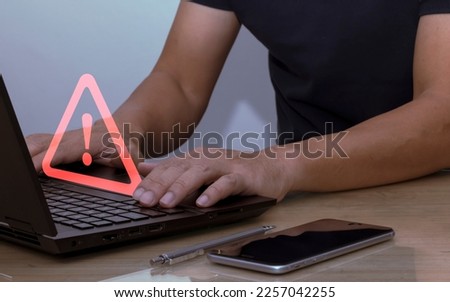 Businessman using laptop computer with triangle warning sign for error alert and maintenance concept Data protection from hackers