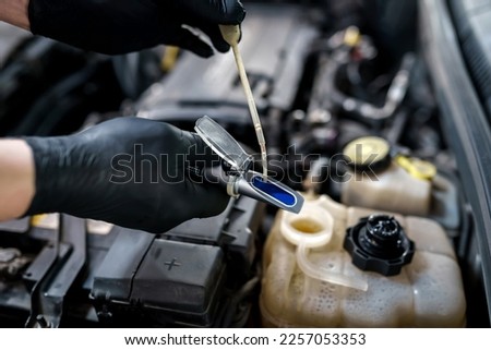 Optical instrument for testing antifreeze, windshield washer fluid and electrolyte density. Mechanic uses car refractometer in service Royalty-Free Stock Photo #2257053353