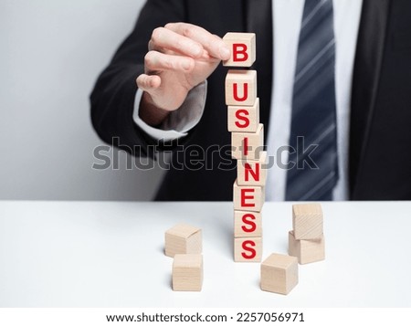 Wooden blocks with red word business. Businessman holding cube. Abstract business, company, growth concept