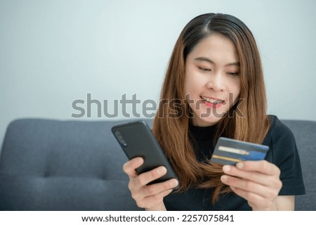 Asian woman using credit card for shopping online on mobile phone applications.