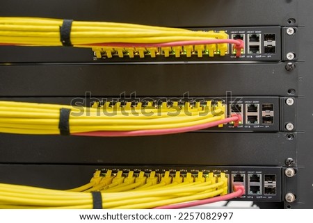 Selective focus on neat and tidy patched network cables, RJ45, connected to the switches and routers mounted on the rack in data centre, networking Royalty-Free Stock Photo #2257082997