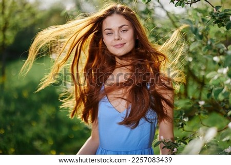 Woman portrait happiness smile with teeth spring in the sun flying hair long red hair, the concept of health and beauty hair sunset