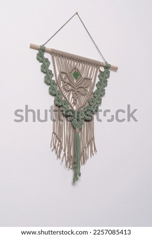 avocado green and sand color macramé wall hanging fiber art decoration with lotus flower symbol. Macrame handmade knotting technique. Cotton rope wood and glass elements