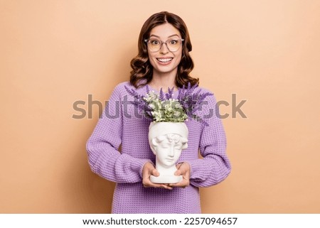 Photo of smart nice lovely woman with curly hairdo wear knit sweater hands hold flowerpot in bust isolated on beige color background