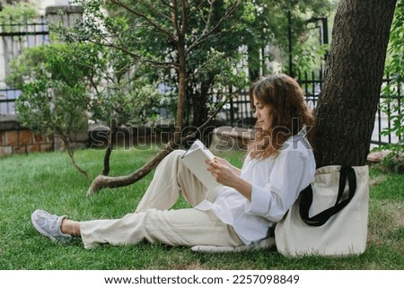 Magazine or book image mockup. The girl relaxes on the lawn in the courtyard of the coffee shop, reads a book. Royalty-Free Stock Photo #2257098849