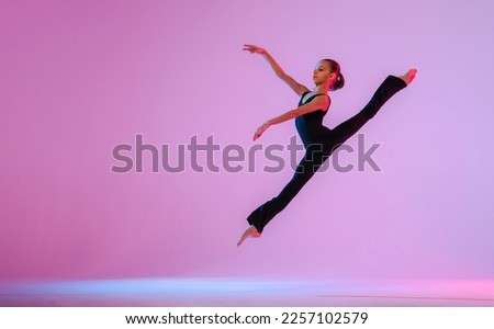 teenage girl in a tight black costume dancing a modern contemporary contemporary dancer isolated on a background in neon light.