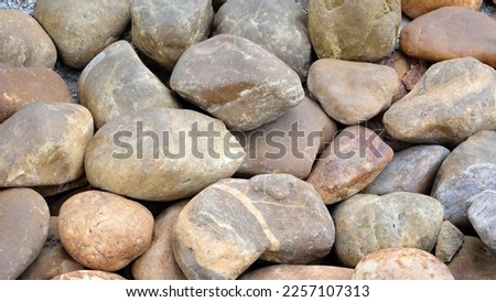 Background pattern of river rocks with rounded corners and some smooth surface.