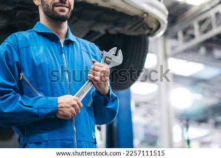 Mechanic hand holding wrench equipment tool in auto repair garage. checking car damage broken, repairing vehicle business. motor technician maintenance after service, copy space