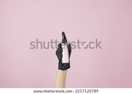 A hand with a black rubber glove holding hair care product on a pink background hair gloss. Banner