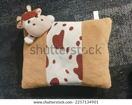 Cute cow stuffed pillow uses a soft and comfortable furry material texture. Pillow design features a cow head icon attached to one corner of the pillow.