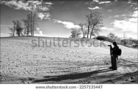 A male photographer taking photos on the sand dune