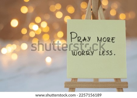 Pray more, worry less, handwritten message on note with blurred bokeh background. A closeup. Christian biblical text to trust and have faith in God and Jesus Christ. Royalty-Free Stock Photo #2257156189