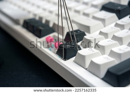 Using a ustensil to remove keycaps from a mechanical keyboard for maintenance