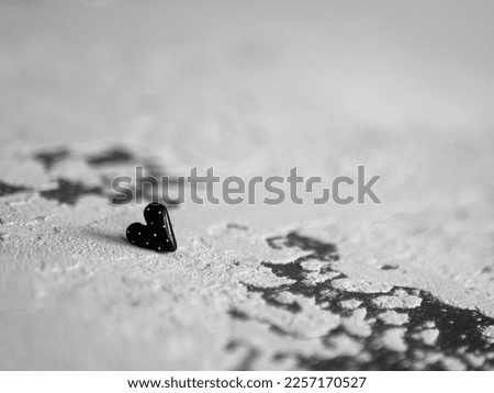 Black heart on a concrete background, selective focus. Concept of morbidity, sorrow, anxiety, unrequited love, affection