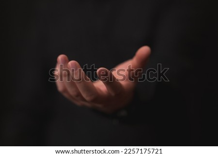 hand outstretched in gesture of giving or receiving, black background, business theme, offer, opportunities. Royalty-Free Stock Photo #2257175721