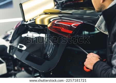 Mechanic and car detailing. Dent removal process from a car trunk. Unrecognizable person using professional equipment to remove dents. High quality photo Royalty-Free Stock Photo #2257181721