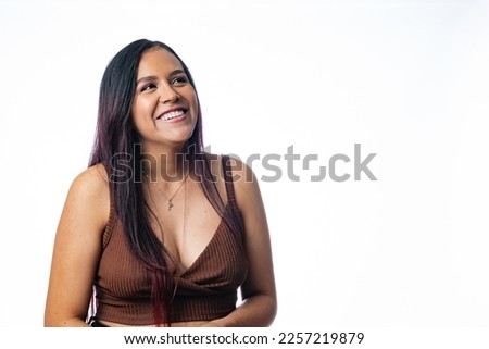 Latin American young woman smiling and looking at the horizon. Girl with a natural smile on a neutral background. Photography with editable background
