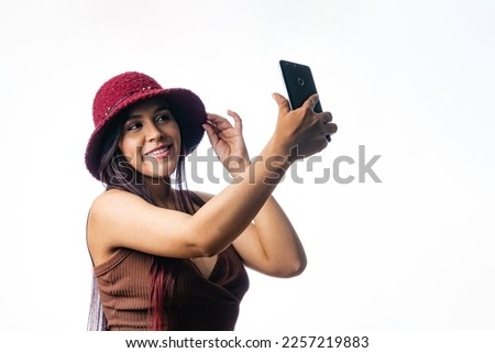 Latin girl taking a picture with her mobile phone. woman in a video call with her mobile device.  Portrait of a Colombian girl on a white background. using app