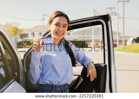 Portrait young asian woman standing smart outside the door of her suv car showing ownership new personal car license proudly legal happy cheerful ready for a carefree journey : Travel safely concept.
