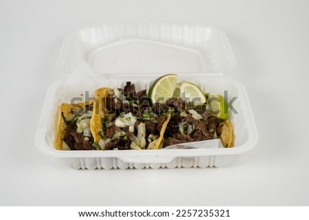 beef tacos in a white take out container 