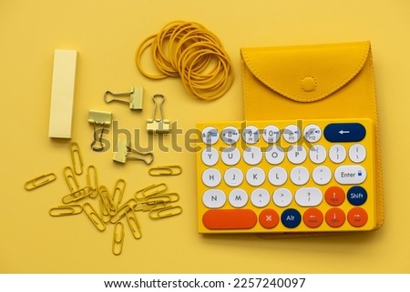 A yellow keyboard with yellow office supplies on a yellow background. The concept of business and minimalism. Monochrome.