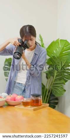 Female Asian photographer taking pictures of healthy food with satisfaction