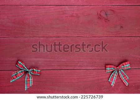 Red plaid Christmas bows border on antique red wooden background barn wall