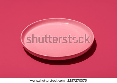 Empty pink plate minimalist on a magenta table. Single plate in bright light on a vibrant colored background