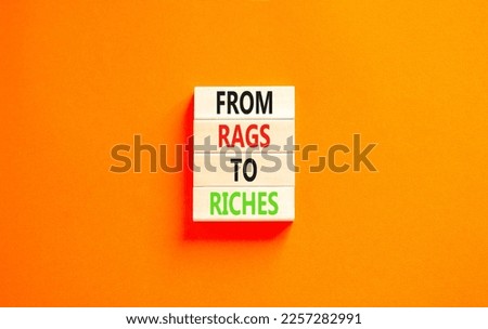 Rags or riches symbol. Concept words From rags to riches on wooden blocks. Beautiful orange table orange background. Business rags or riches concept. Copy space.